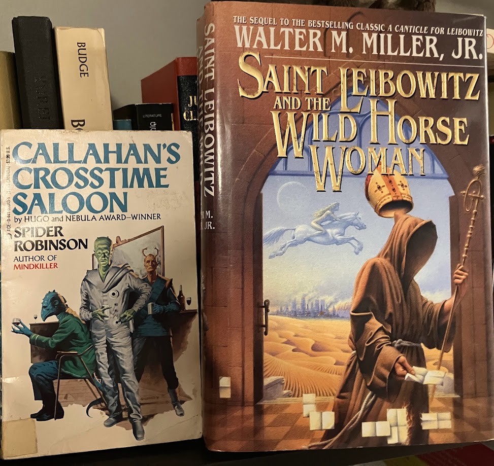 a paperback copy of Callahan's Crosstime Saloon and a hardcover of Saint Leibowitz and the Wild Horse Woman